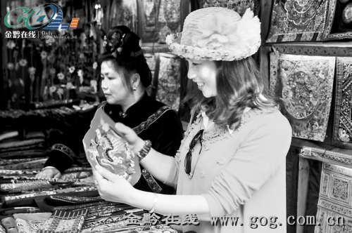 　　图为一名女游客在西江千户苗寨购买刺绣工艺品。